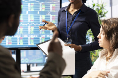 Advisory board members meeting in boardroom to establish future development plan, ensuring expansion goals for the multinational company. Studying big data insights to make informed decisions.