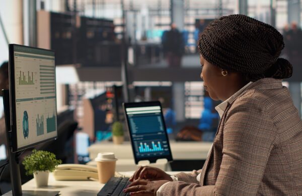 Professional business staff managing financial data to solve tasks for development, report writing at desk. Focused female manager using expertise to accomplish administrative tasks. Camera A.