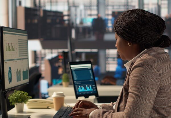 Professional business staff managing financial data to solve tasks for development, report writing at desk. Focused female manager using expertise to accomplish administrative tasks. Camera A.